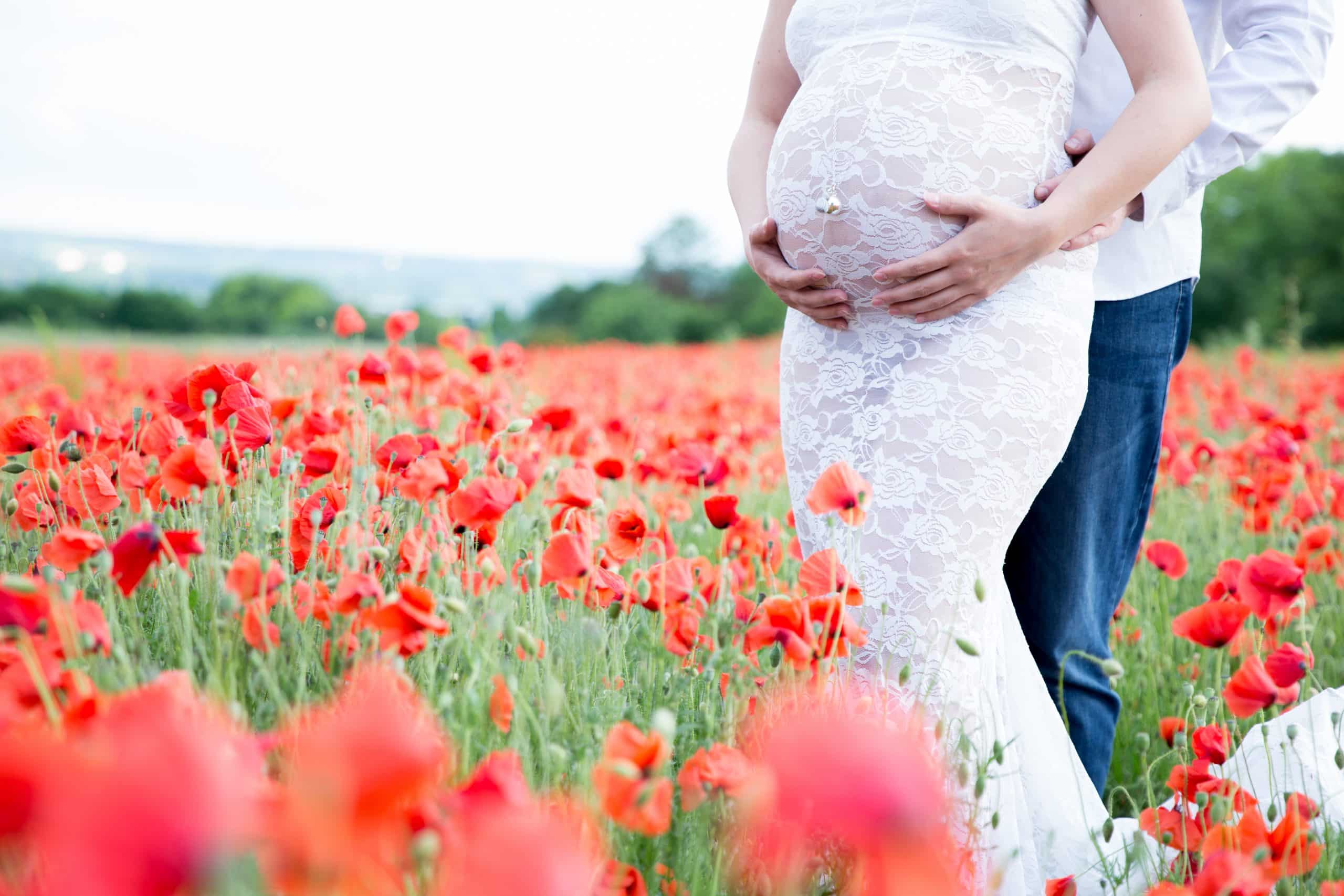 photo futurs parents dans champ de coquelicots